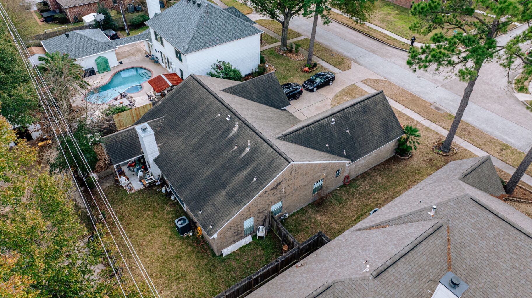 Aerial view of weathered, dark-stained Valley Palms roof before replacement in Houston