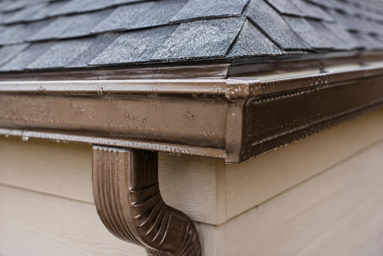 Bronze seamless gutter corner and downspout on a Houston home after rain