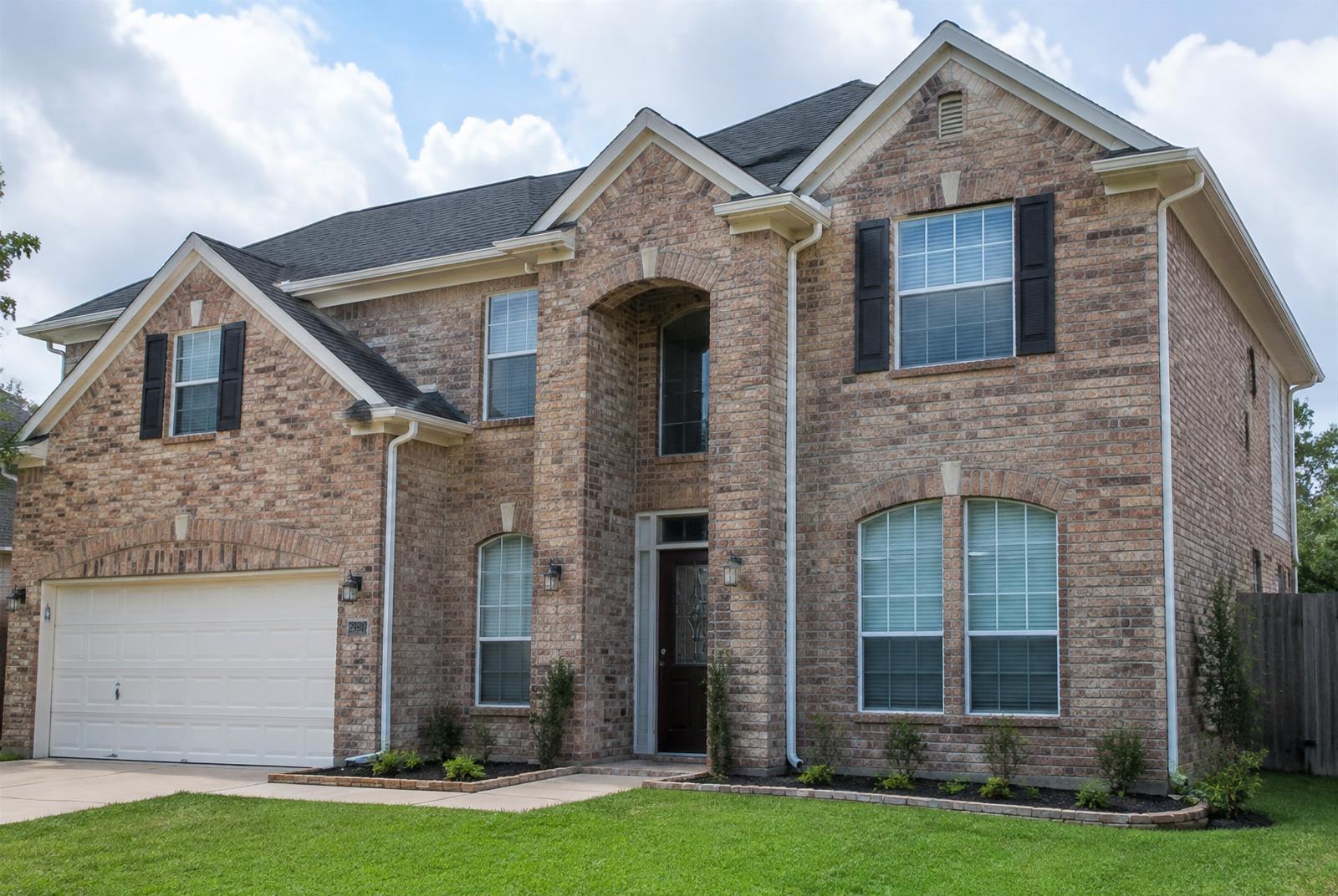 White seamless gutters and downspouts on a two-story Houston brick home